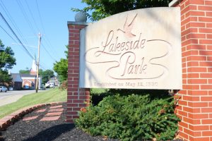 Lakeside Park entrance sign carved in stone, flanked by brick columns and landscaping.