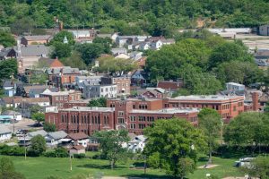 Aerial view of a small town with a large red brick school building in the foreground, surrounded by trees and residential streets.