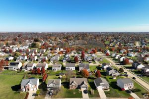 Aerial view of a suburban neighborhood in autumn with colorful trees and streets lined with houses in fall colors.